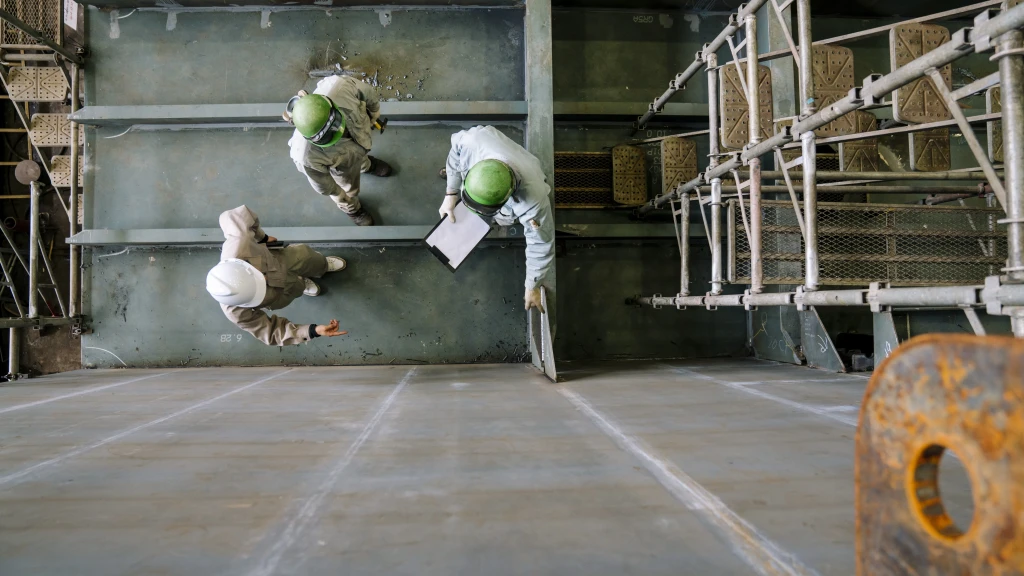 Luftaufnahme von drei Männern in einer Fabrikhalle.