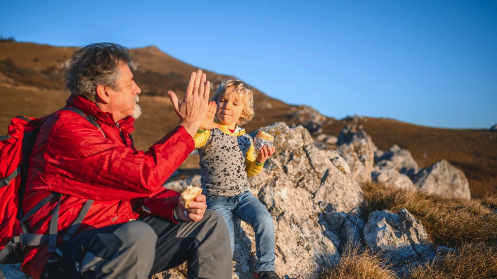 Grandpa and grandson highfive in the mountains