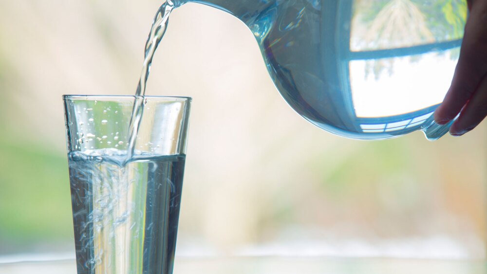 water being poured into glass from jug of water