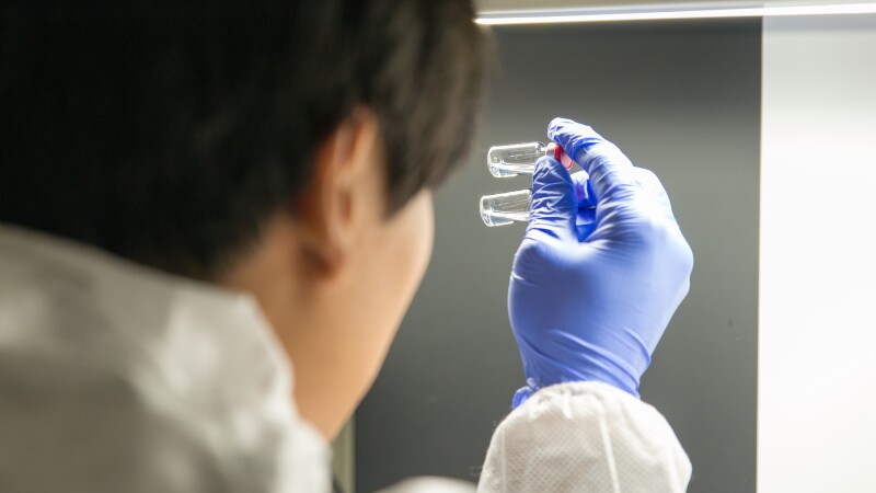 Individual vaccine vials undergoing visual inspection and quality assurance