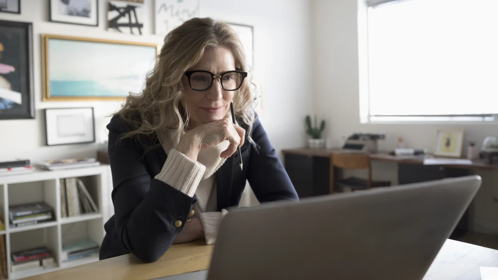 Eine Frau sitzt in ihrem Wohnzimmer im Homeoffice vor ihrem Laptop.