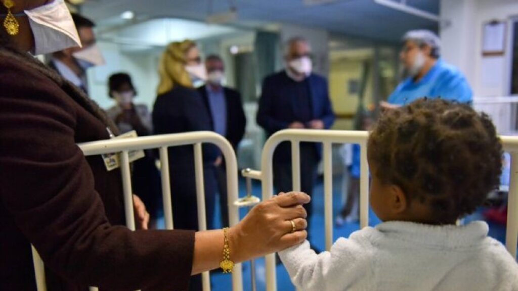 A woman holding her baby's hand in a hospital