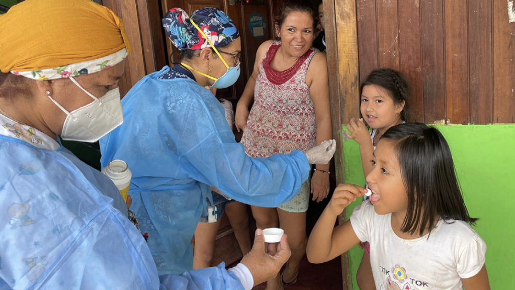 Two nurses in PPE delivering medicine to a family on their doorstep