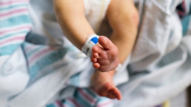 A newborn baby's feet with a hospital bracelet around its ankle