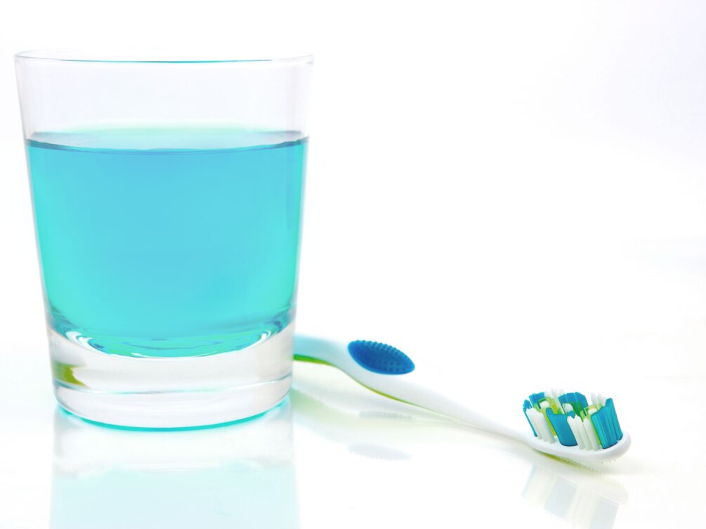 mouthwash in glass next to toothbrush