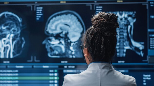 A view of a doctor from behind, as they look at brain scans